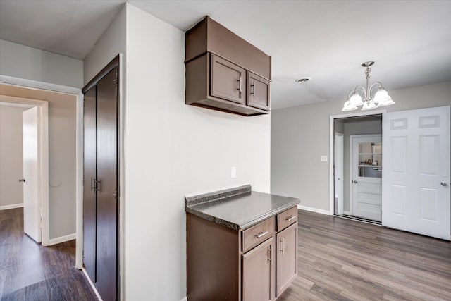 kitchen featuring dark countertops, baseboards, hanging light fixtures, a notable chandelier, and dark wood-style flooring