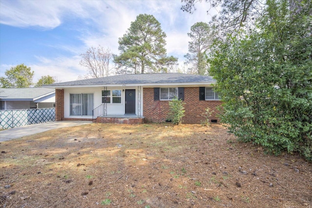 ranch-style house with a shingled roof, fence, brick siding, and crawl space