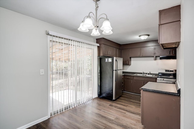 kitchen with dark countertops, stainless steel appliances, dark wood-type flooring, and a sink