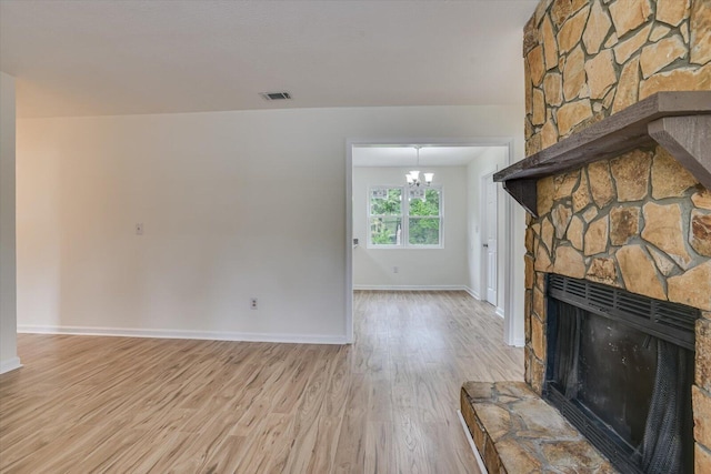 unfurnished living room with a fireplace, light hardwood / wood-style flooring, and a notable chandelier