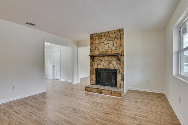 unfurnished living room featuring a healthy amount of sunlight, a fireplace, and light hardwood / wood-style flooring