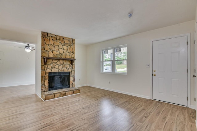 unfurnished living room featuring a stone fireplace, ceiling fan, and light hardwood / wood-style floors