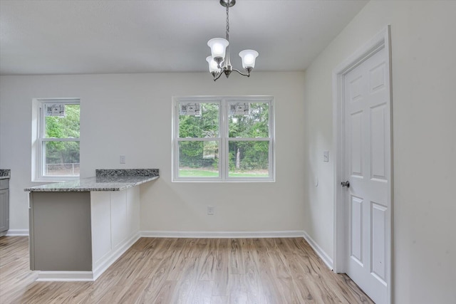 interior space featuring decorative light fixtures, light hardwood / wood-style floors, a wealth of natural light, and an inviting chandelier