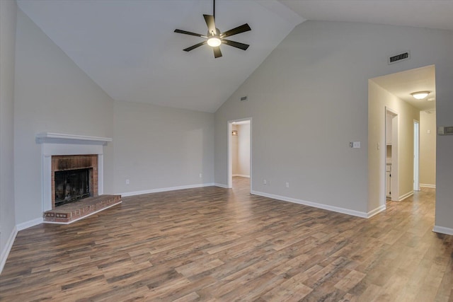 unfurnished living room with visible vents, a ceiling fan, wood finished floors, baseboards, and a brick fireplace