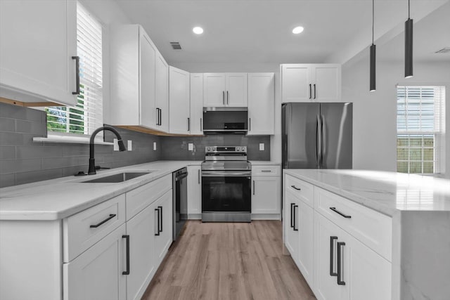 1116 Miller St, Augusta, GA 30901 - kitchen with appliances with stainless steel finishes, a sink, light wood finished floors, white cabinetry, and decorative backsplash