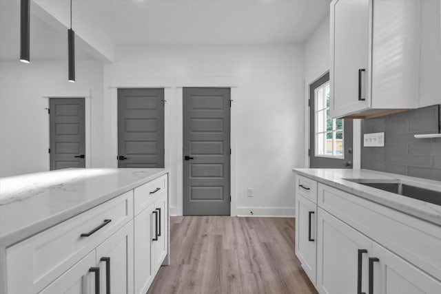 1116 Miller St, Augusta, GA 30901 - kitchen with decorative backsplash, white cabinets, light wood-style floors, light stone countertops, and baseboards