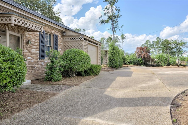 view of property exterior featuring brick siding, driveway, and an attached garage