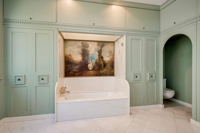 full bathroom featuring a closet, a garden tub, toilet, marble finish floors, and baseboards
