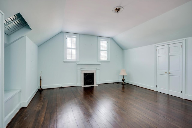 bonus room featuring dark wood-style floors, a fireplace with flush hearth, lofted ceiling, and baseboards