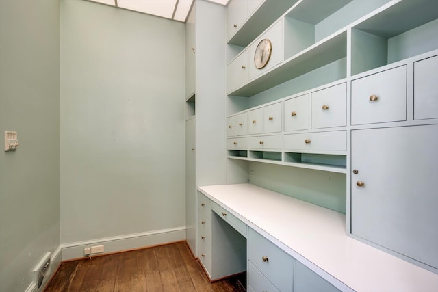 unfurnished office with built in study area, dark wood finished floors, and baseboards
