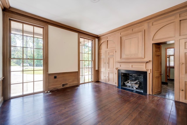 unfurnished living room featuring dark wood-type flooring, a fireplace, and wainscoting
