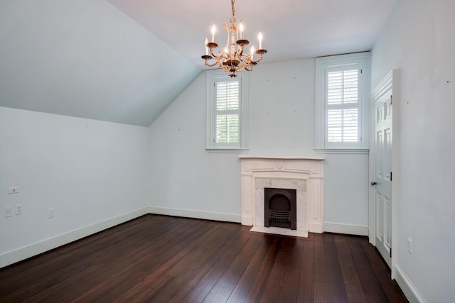unfurnished living room featuring dark wood-type flooring, a chandelier, healthy amount of natural light, a premium fireplace, and vaulted ceiling