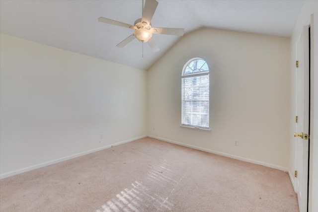 spare room with light carpet, ceiling fan, baseboards, and vaulted ceiling