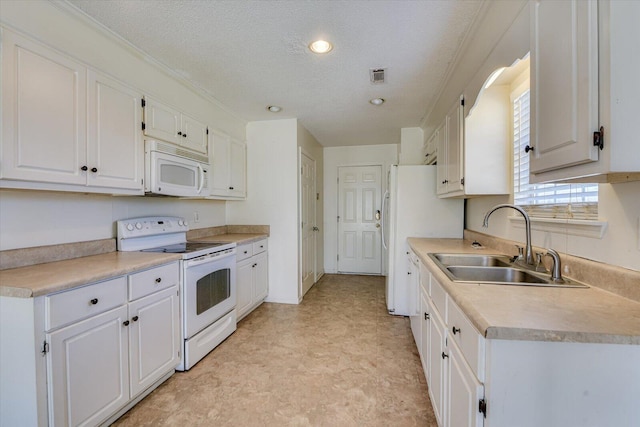 kitchen featuring white appliances, visible vents, white cabinets, light countertops, and a sink