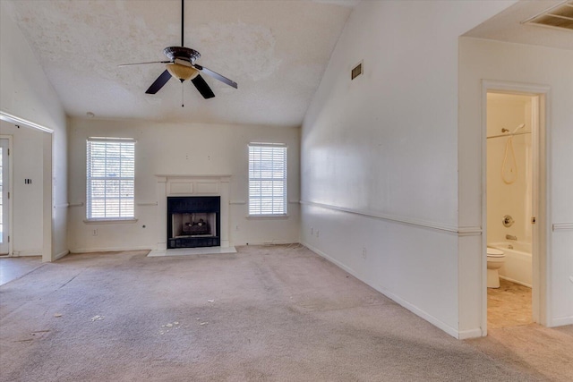 unfurnished living room featuring carpet, lofted ceiling, visible vents, a fireplace with raised hearth, and a textured ceiling