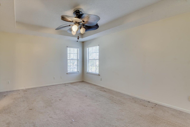 carpeted spare room with a ceiling fan, a tray ceiling, a textured ceiling, and baseboards