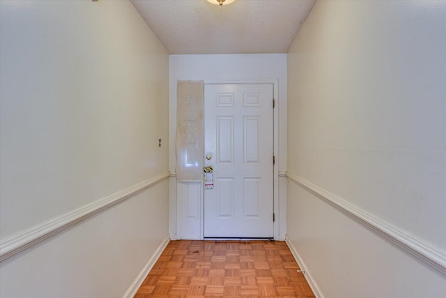 doorway with a textured ceiling and baseboards