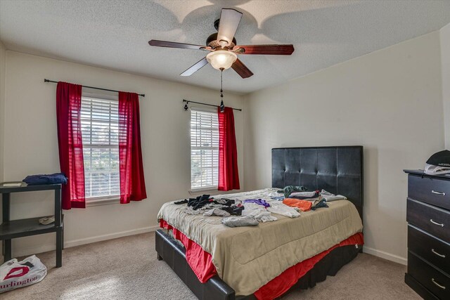 carpeted bedroom with a textured ceiling, ceiling fan, and baseboards