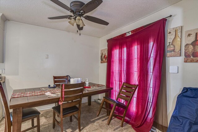 dining area featuring ceiling fan and a textured ceiling