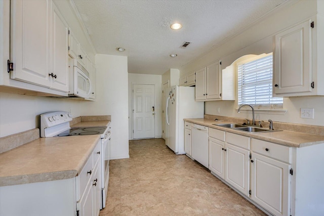 kitchen with white appliances, a sink, visible vents, and white cabinetry