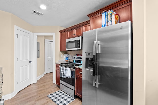 kitchen featuring light stone countertops, appliances with stainless steel finishes, tasteful backsplash, a textured ceiling, and light hardwood / wood-style flooring