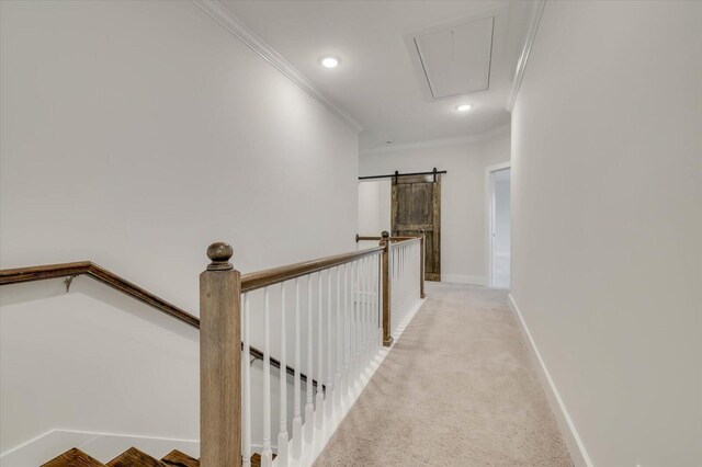 hall featuring a barn door, crown molding, and light carpet