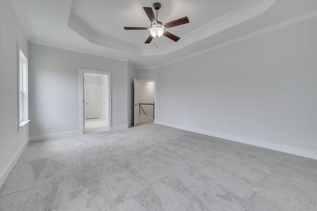 unfurnished bedroom featuring ceiling fan, a raised ceiling, crown molding, and light carpet