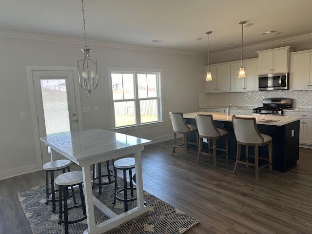 dining room with dark hardwood / wood-style flooring, an inviting chandelier, crown molding, and sink