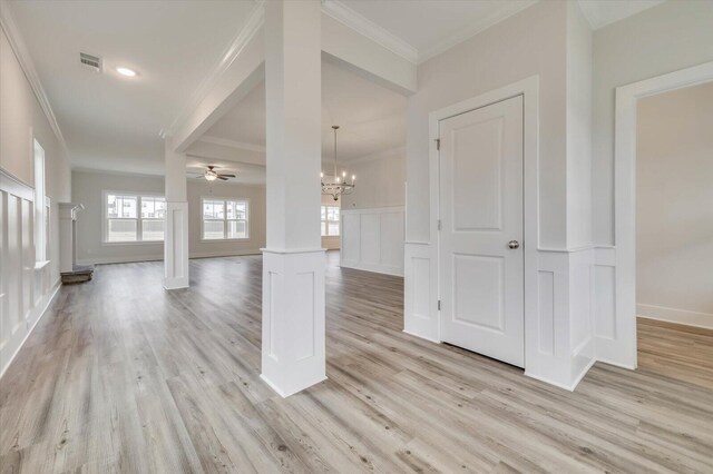 interior space featuring ornate columns, crown molding, and light wood-type flooring