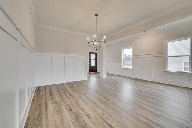 spare room with crown molding, light hardwood / wood-style floors, and a notable chandelier