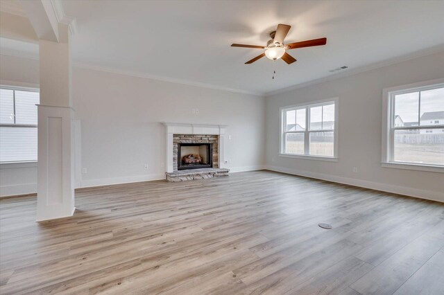 unfurnished living room with a stone fireplace, ceiling fan, light hardwood / wood-style flooring, and ornamental molding