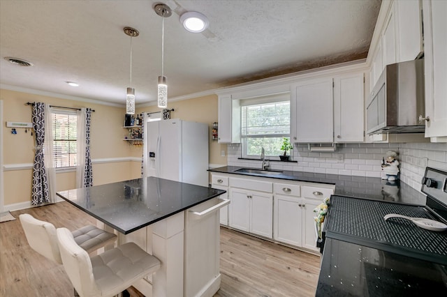 141 Whaley St, Warrenville, SC 29851 - kitchen with white fridge with ice dispenser, black electric range, stainless steel microwave, dark countertops, and light wood-style flooring