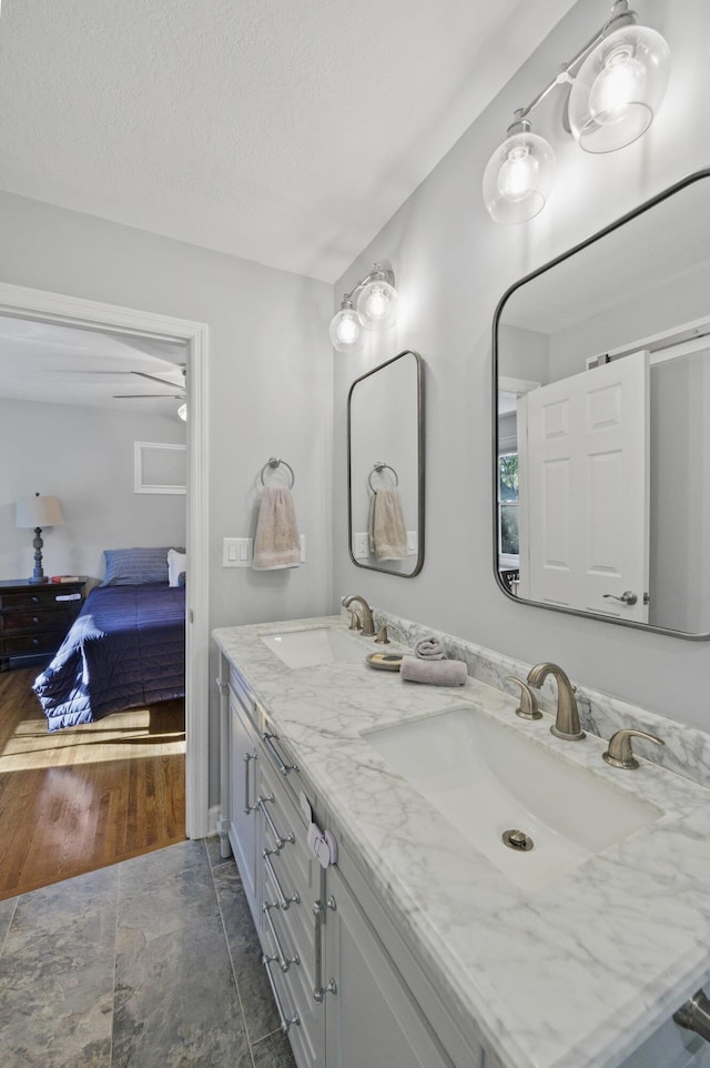 bathroom featuring vanity, ceiling fan, and a textured ceiling