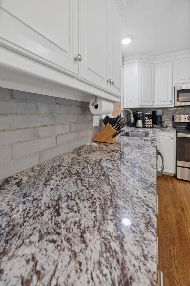 kitchen featuring white cabinetry, sink, light stone counters, and appliances with stainless steel finishes