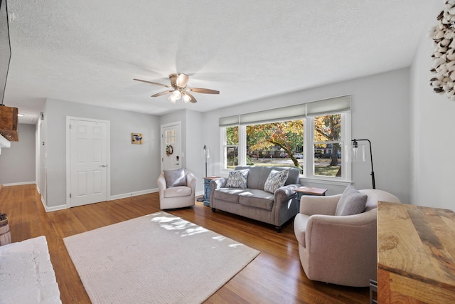 living room with hardwood / wood-style flooring, ceiling fan, and a textured ceiling