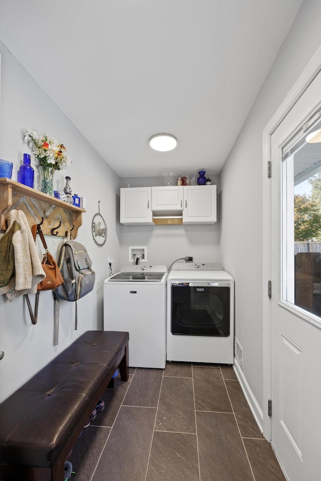 clothes washing area with dark tile patterned flooring, cabinets, and independent washer and dryer