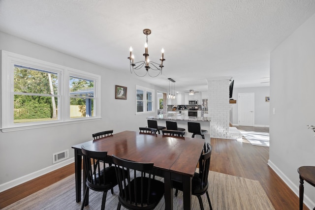 dining space featuring a textured ceiling, dark hardwood / wood-style flooring, and an inviting chandelier