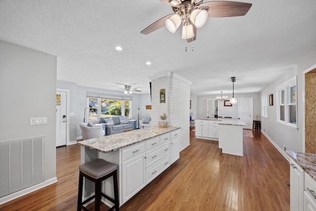 kitchen featuring pendant lighting, a center island, white cabinetry, and hardwood / wood-style floors