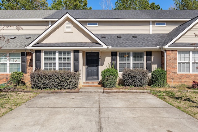 view of front of property with stucco siding, a shingled roof, and brick siding