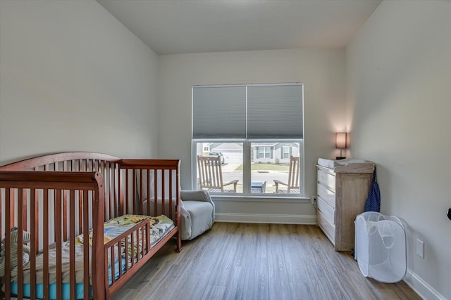 bedroom with a crib and light wood-type flooring