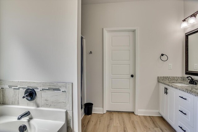 bathroom featuring hardwood / wood-style floors, vanity, and a washtub