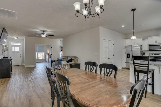 dining area featuring ceiling fan with notable chandelier and light hardwood / wood-style flooring