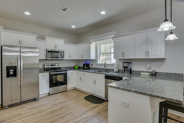 kitchen with kitchen peninsula, stainless steel appliances, white cabinetry, and sink