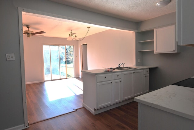 kitchen with white cabinetry, sink, dark hardwood / wood-style floors, kitchen peninsula, and ceiling fan with notable chandelier