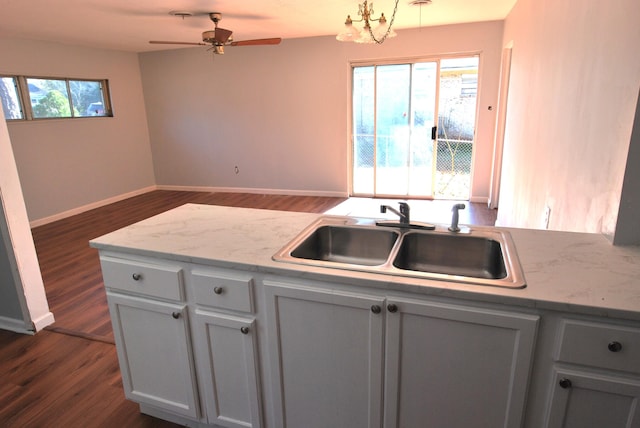 kitchen featuring ceiling fan, dark hardwood / wood-style floors, light stone counters, and sink