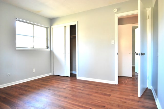 unfurnished bedroom with a closet and dark wood-type flooring