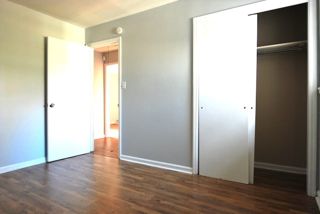 unfurnished bedroom featuring a closet and dark wood-type flooring