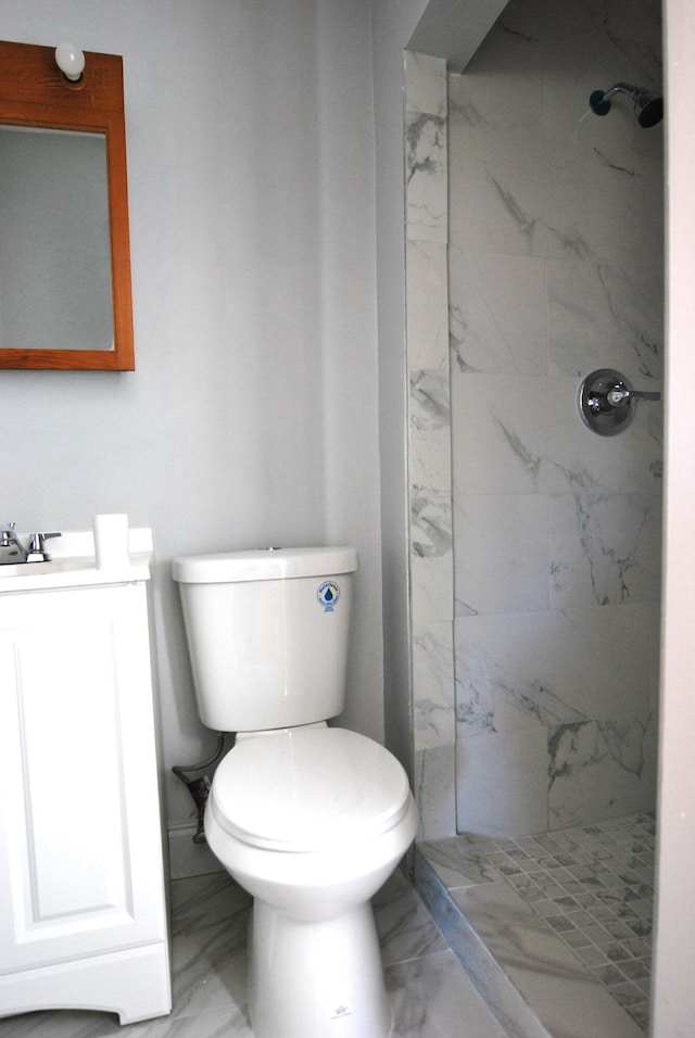 bathroom with a tile shower, vanity, and toilet