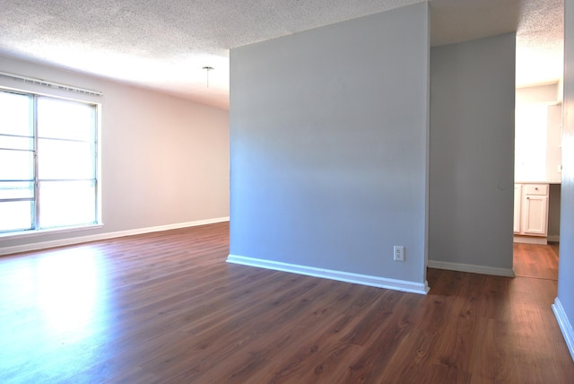 empty room with a healthy amount of sunlight, dark hardwood / wood-style floors, and a textured ceiling