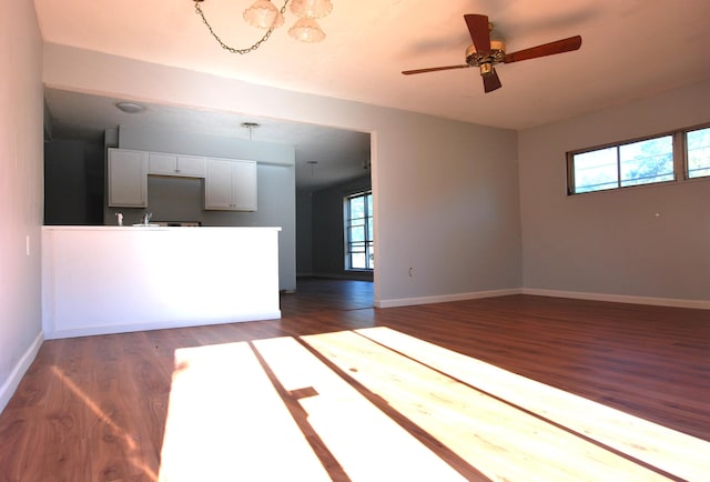 unfurnished living room featuring ceiling fan and dark hardwood / wood-style flooring